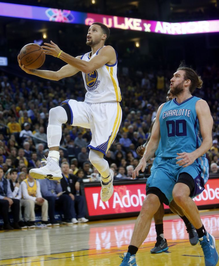 Golden State Warriors Stephen Curry scores in front of Charlotte Hornets Spencer Hawes in 2nd quarter during NBA game at Oracle Arena in Oakland Calif. on Monday
